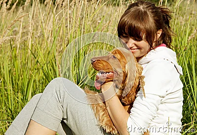 Chica joven feliz que abraza su perro en GR verde.