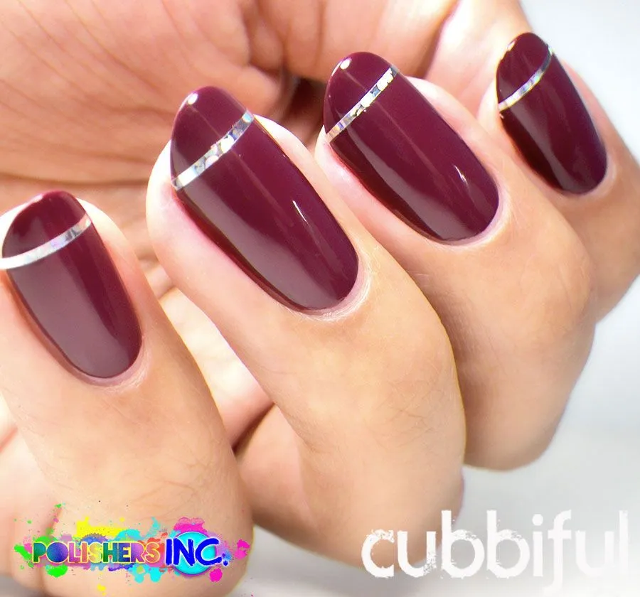 Encantadoras uñas en color vino decoradas con una línea plateada en las puntas.
