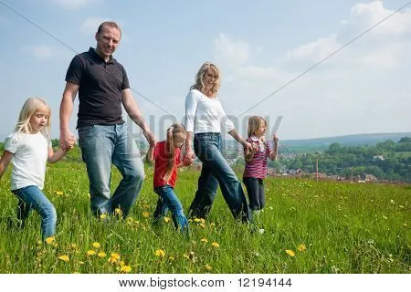 Familia feliz con niños caminando por un prado con flores de ...