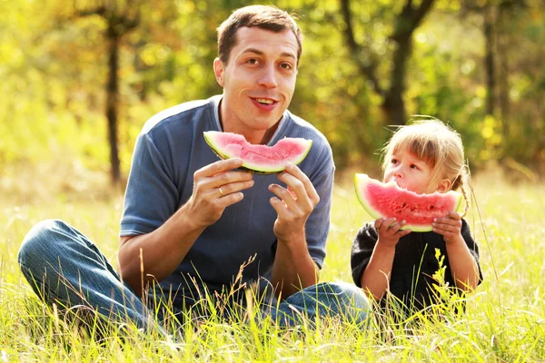 hermosa niña con papá en la naturaleza comiendo sandía — Foto ...