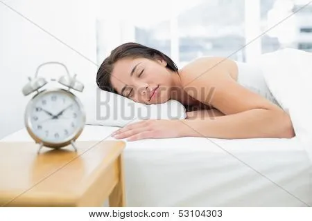 Joven mujer durmiendo en la cama con despertador borrosa en la ...