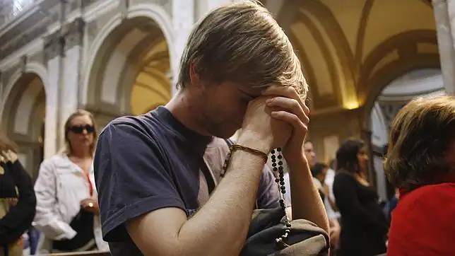 Un joven rezando en una iglesia - abcdesevilla.es