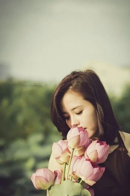 Mujer oriental oliendo el aroma de una flor | Imagenes Sin Copyright