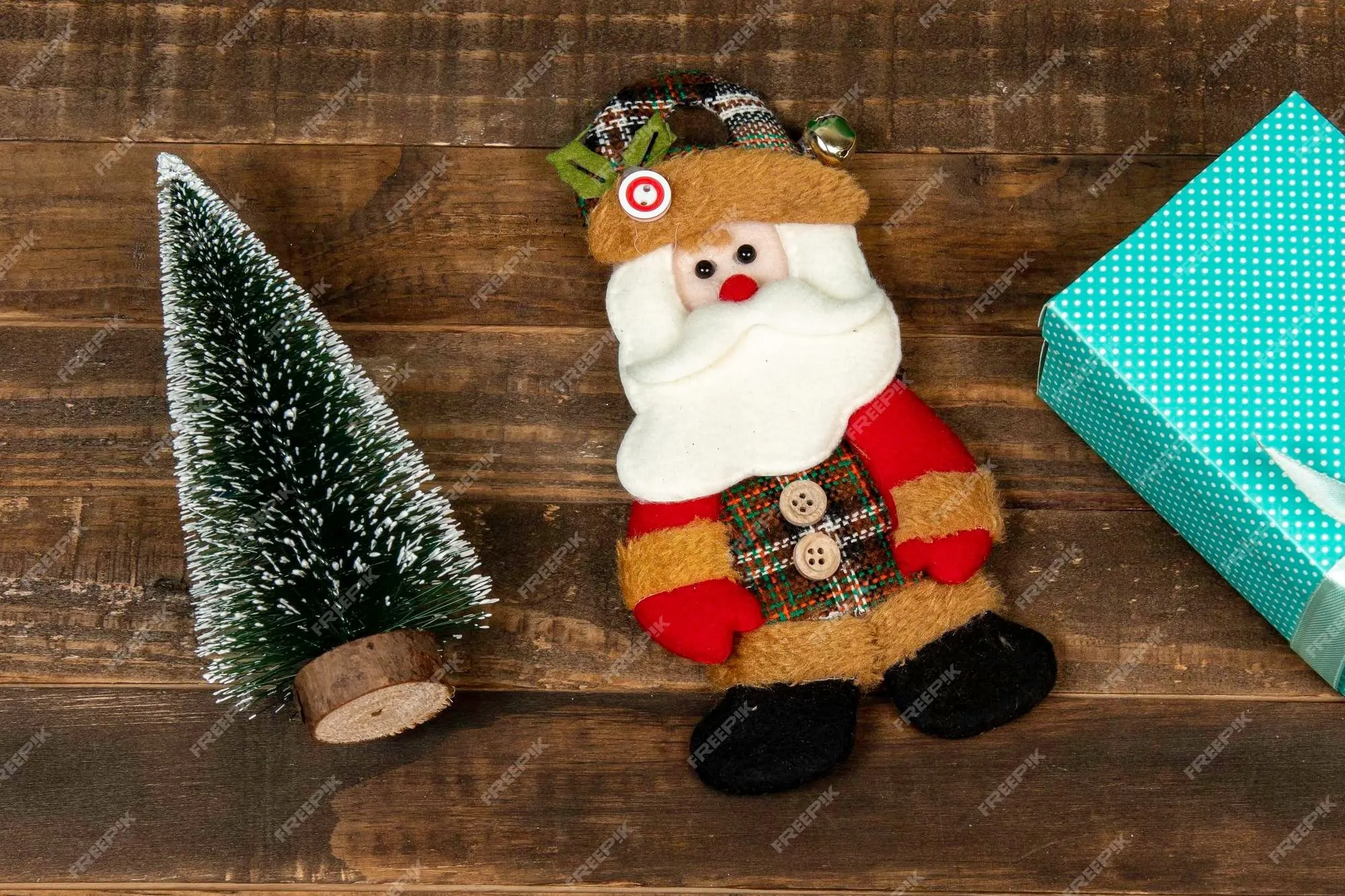 Muñeco de fieltro de santa claus, vestido con ropa de invierno con un árbol  y una caja de regalo, | Foto Premium