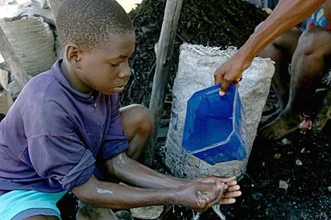 Un niño haitiano lavandose las manos. | AFP