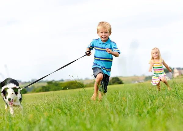 niños felices corriendo al aire libre con perro — Foto stock ...