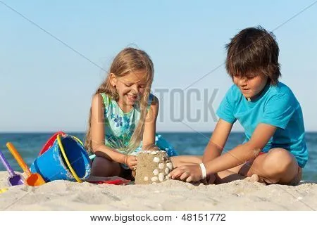 Niños jugando en la playa construyendo un castillo de arena ...