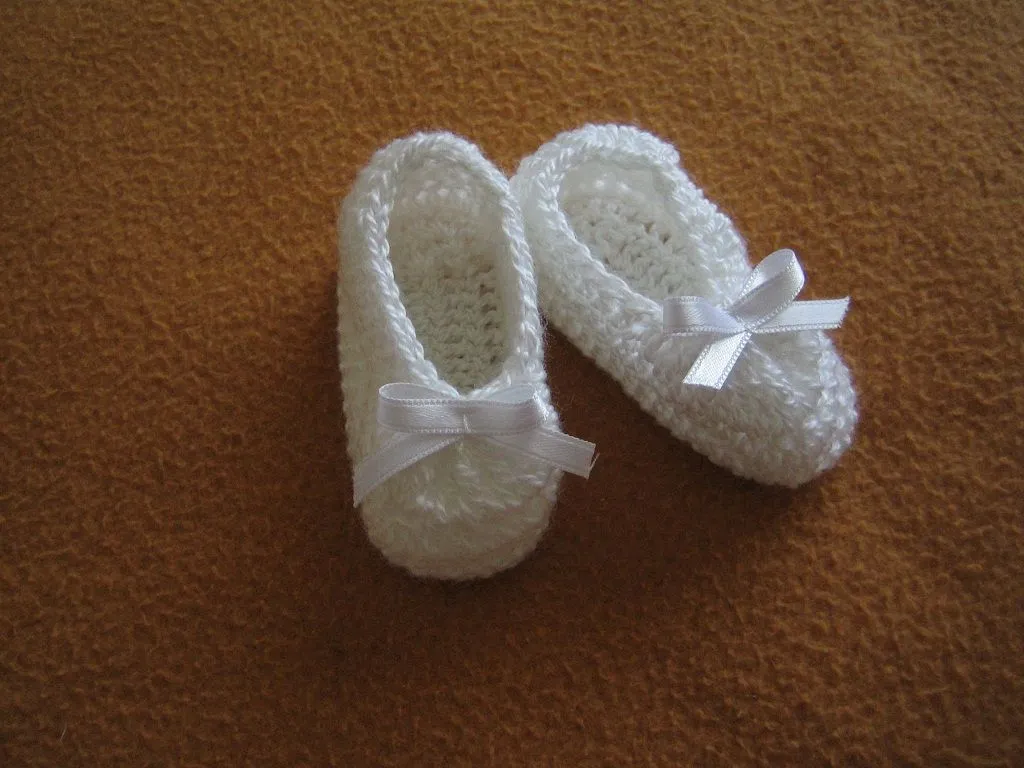 Patucos para bebé tejidos a ganchillo en hilo blanco con lacito.