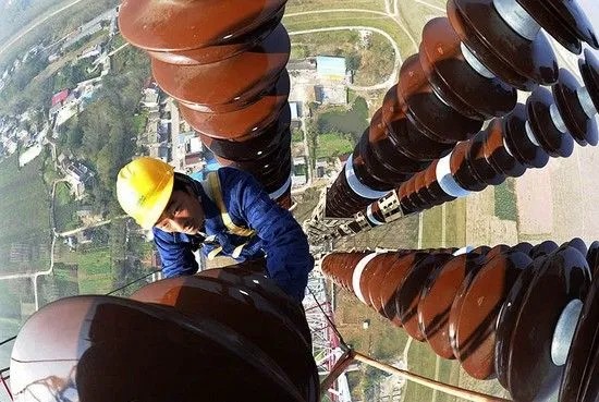 Un trabajador revisando un poste de electricidad en Anqing, provincia de Anhui, China. China Daily. Reuters.