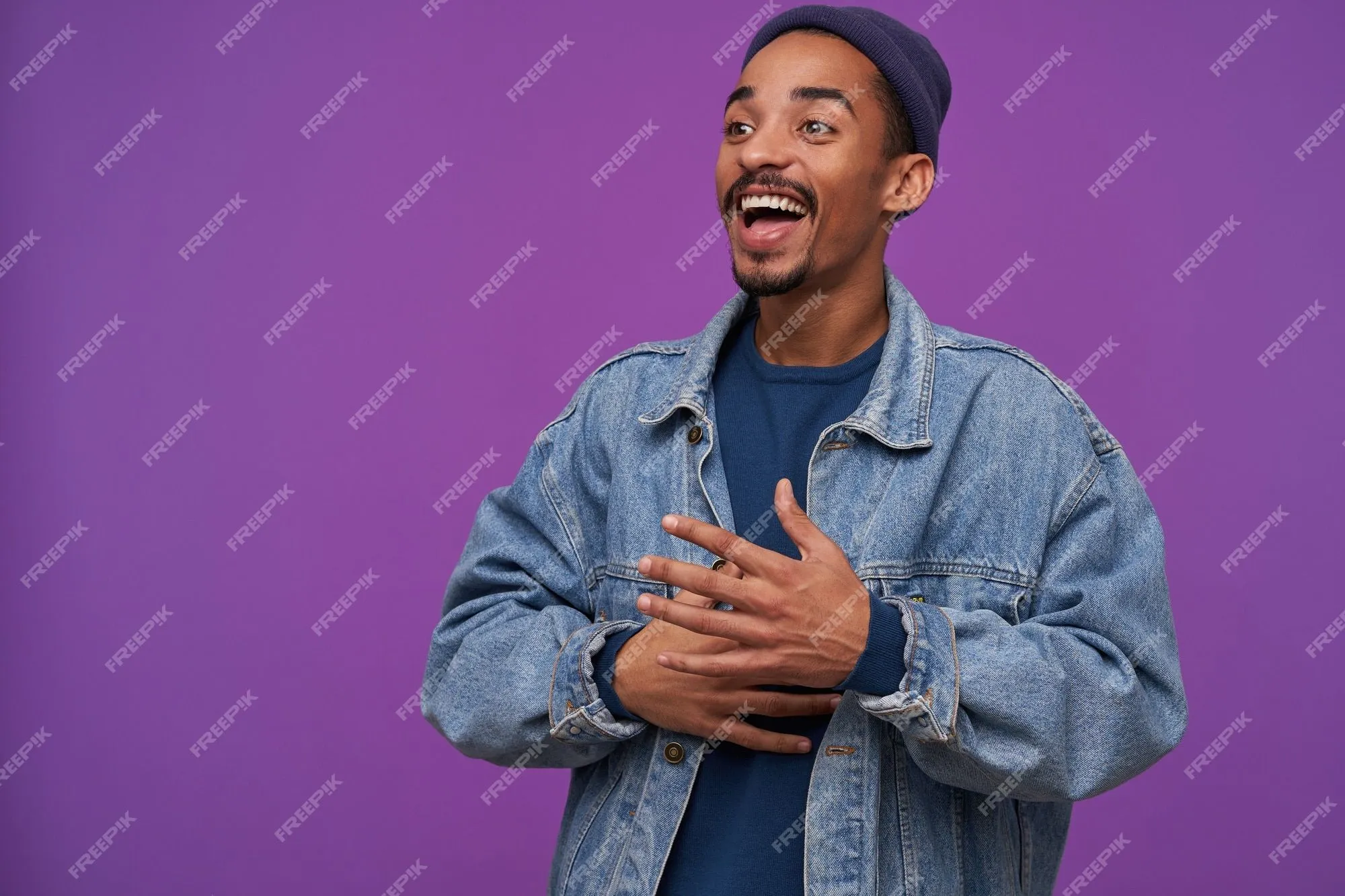 Alegre joven guapo moreno barbudo de piel oscura sonriendo con alegría y mirando felizmente a un lado, vestido con ropa casual mientras posa sobre una pared púrpura | Foto Gratis Alegre joven guapo moreno barbudo de piel oscura sonriendo con alegría y mirando felizmente a un lado, vestido con ropa casual mientras posa sobre una pared púrpura | Foto Gratis