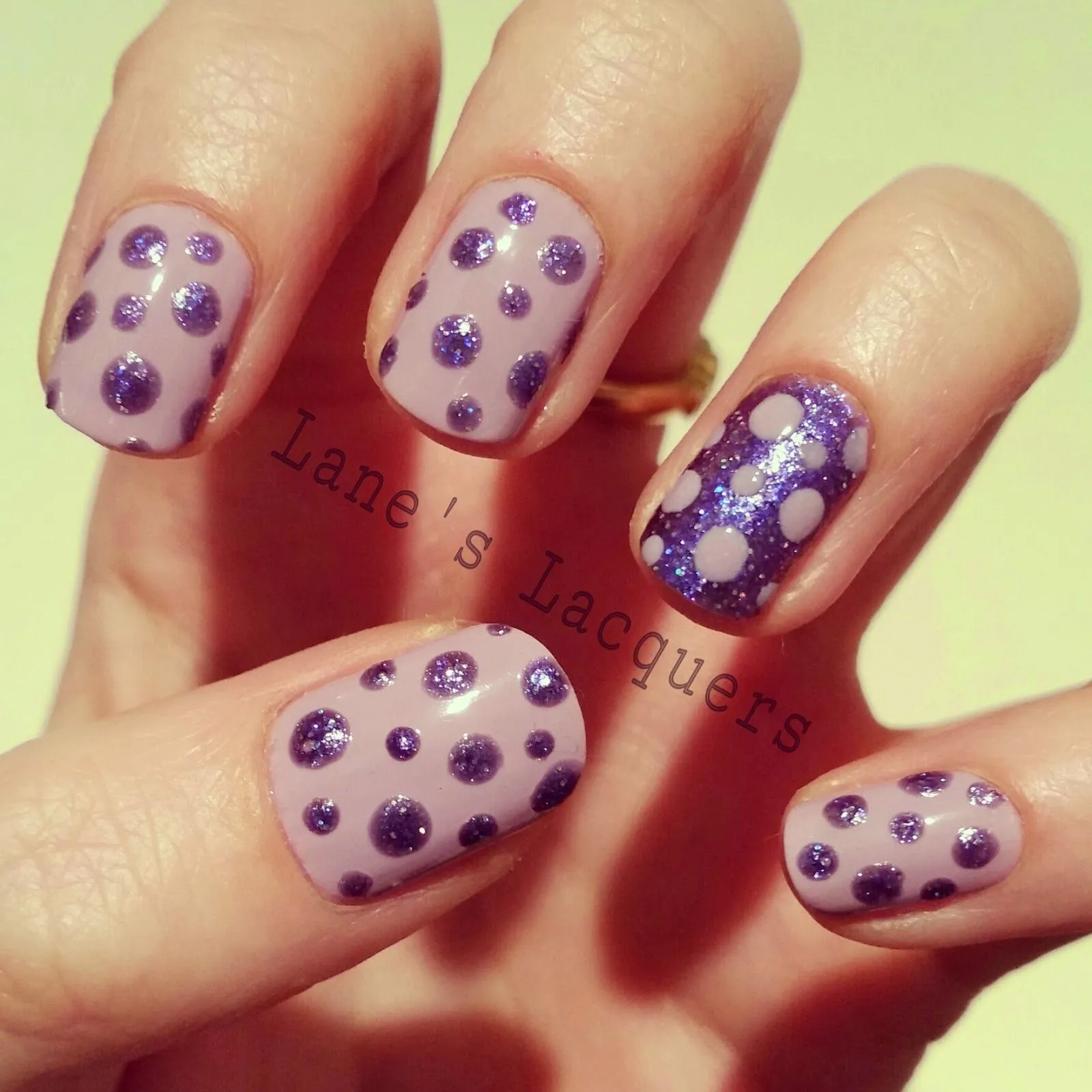 Bellas uñas en tonos morados decoradas con diseños de lunares.
