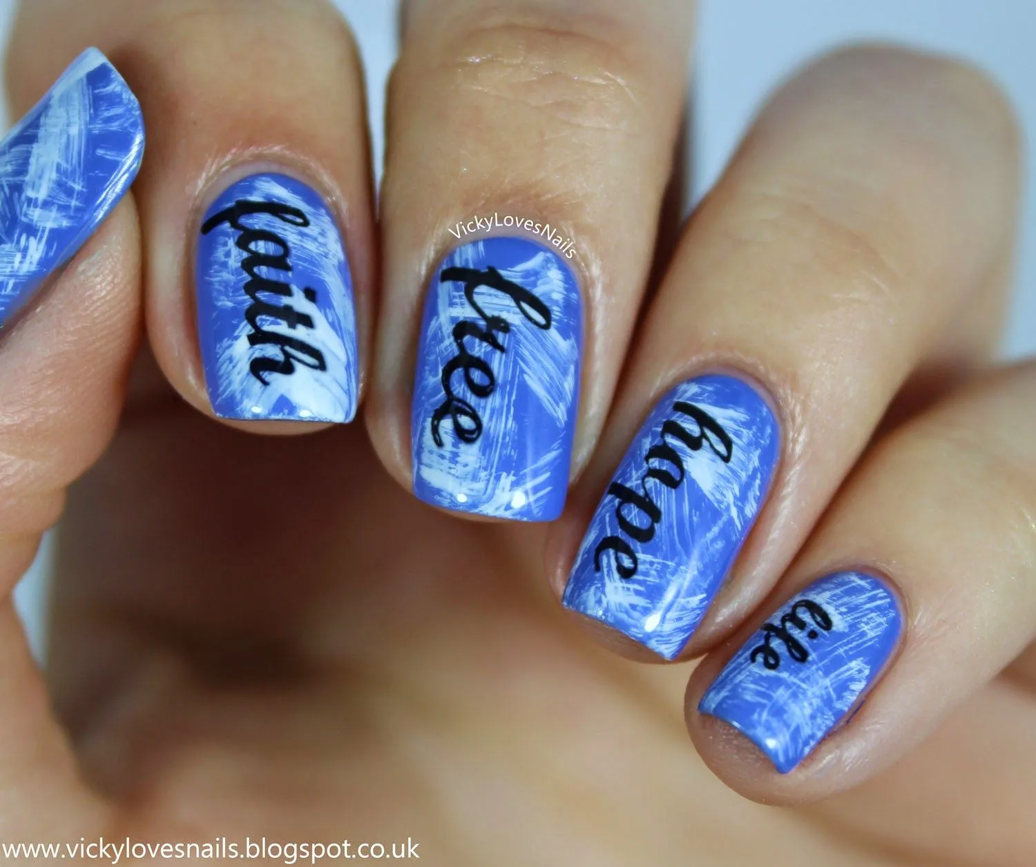 Bonitas uñas manchadas en azul y blanco con letras en color negro.