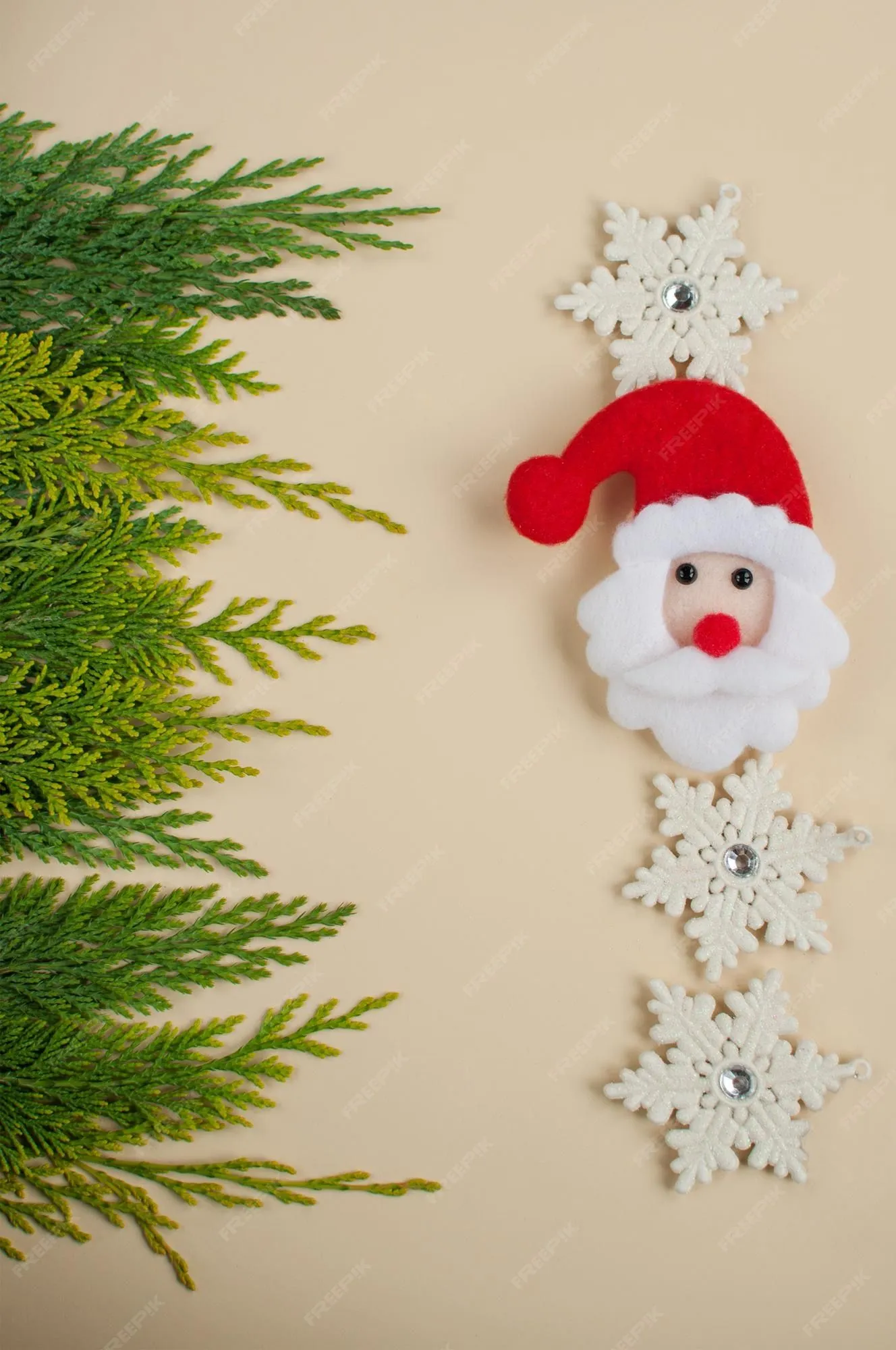 La cara de papá noel hecha de fieltro sobre el fondo de ramas de tuya verde y una decoración de copos de nieve blancos con un lugar para el texto en formato vertical | Foto Premium La cara de papá noel hecha de fieltro sobre el fondo de ramas de tuya verde y una decoración de copos de nieve blancos con un lugar para el texto en formato vertical | Foto Premium