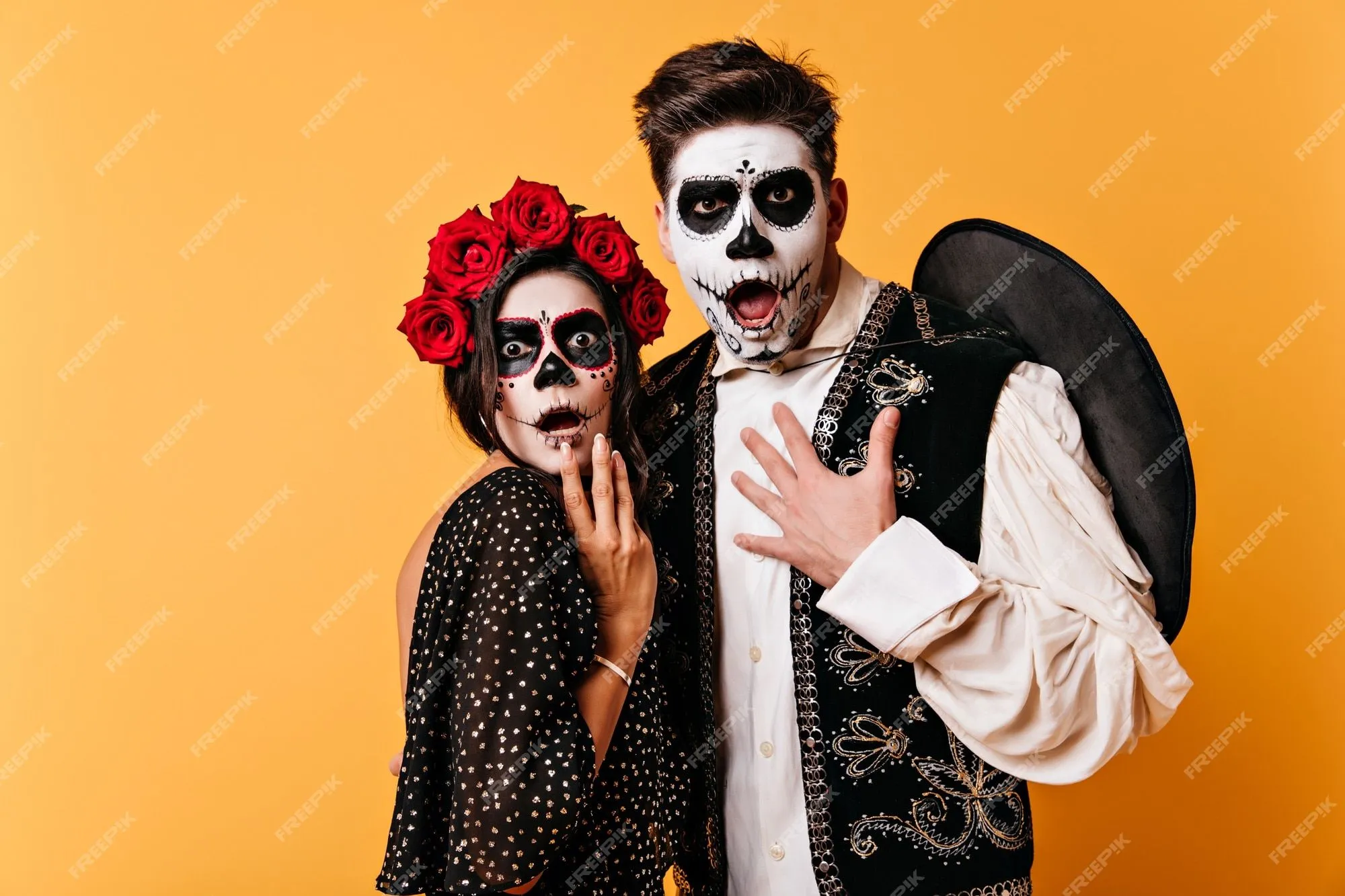 Chico y chica asombrados con caras pintadas para halloween se ven  asustados. foto de pareja en trajes nacionales mexicanos en pared aislada.  | Foto Gratis