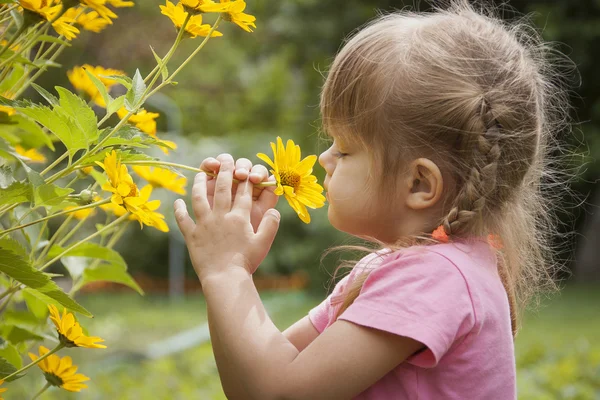 flor de una niña de tres años oliendo amarillo — Foto stock ...