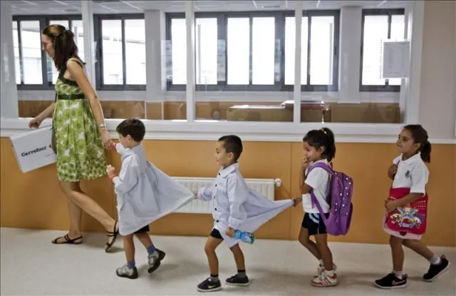 Un grupo de niños en fila se dirigen a clase con la profesora al ... Un grupo de niños en fila se dirigen a clase con la profesora al ...