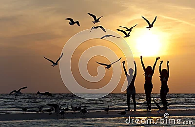 Tres mujeres jóvenes que bailan en la playa en la puesta del sol. Tres mujeres jóvenes que bailan en la playa en la puesta del sol.