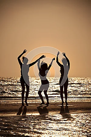 Tres mujeres jovenes que bailan en la playa en la puesta del sol. Tres mujeres jovenes que bailan en la playa en la puesta del sol.