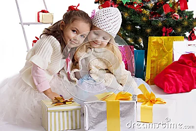 Niñas preciosas con los presentes debajo del árbol de navidad Niñas preciosas con los presentes debajo del árbol de navidad