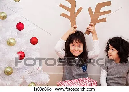 Dos niñas, preparación para navidad, juego, con, cartón, reno, cornamenta Dos niñas, preparación para navidad, juego, con, cartón, reno, cornamenta