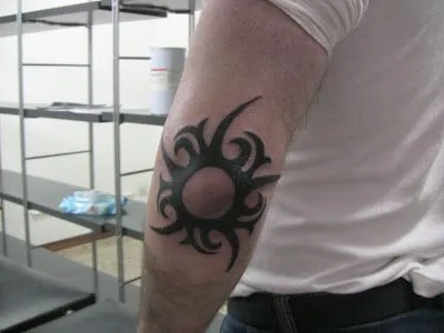 norbek tattoo: Sol tribal en el codo.