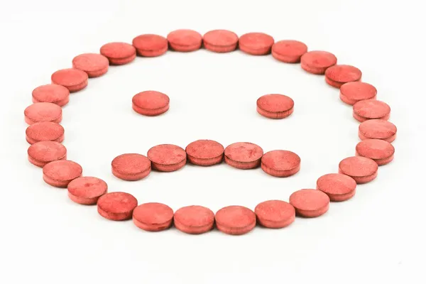 Pastillas rojas dispuestas en una carita triste — Foto stock ...