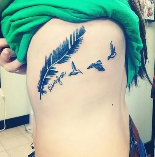 Pequeño tatuaje de una pluma y tres pájaros volando con la frase ...