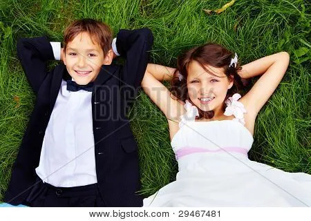 Retrato de sonrientes niños novios tumbados en la hierba verde y ...