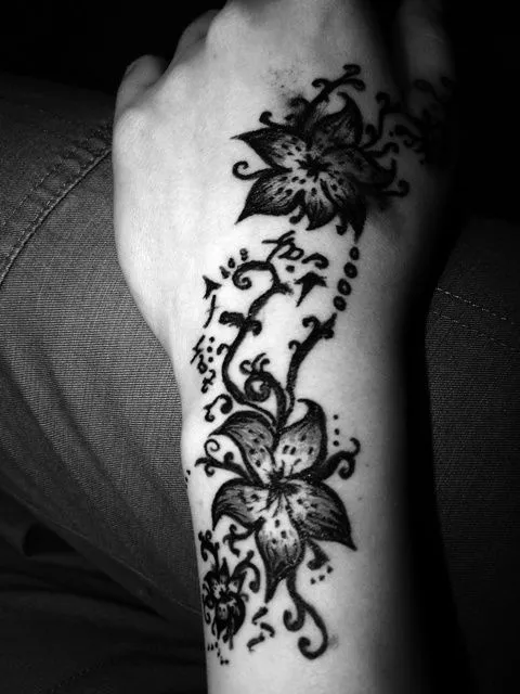 Tatuaje en la mano izquierda de flores subiendo hacia el brazo Tatuaje en la mano izquierda de flores subiendo hacia el brazo