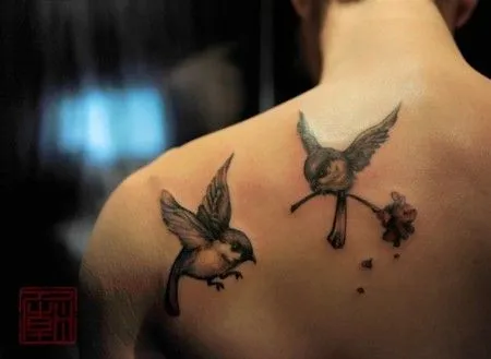 TATUAJE DE UNOS PÁJAROS, UNO DE ELLOS TRANSPORTANDO UNA FLOR