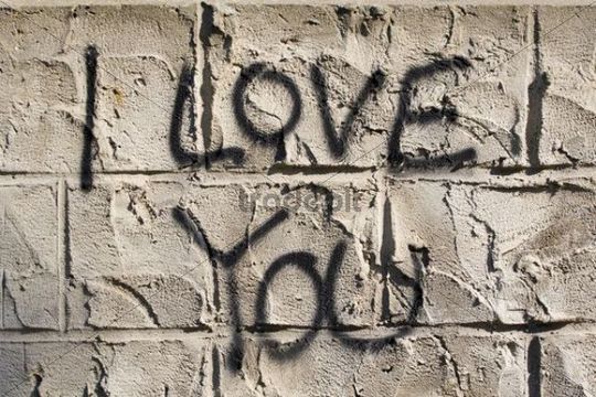 The words I love you as graffiti on the outside walls of a house - ...