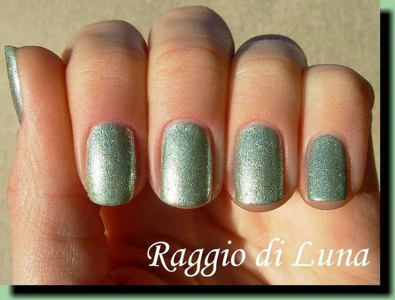 Uñas decoradas en verde pastel con brillos.